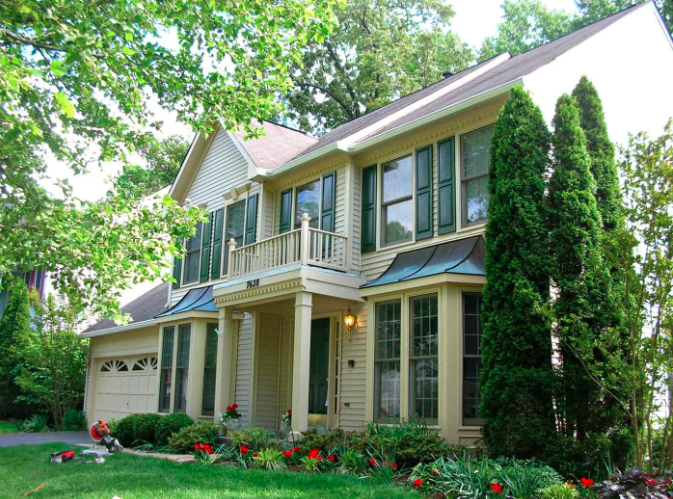 a house in Rockville with a roof and gutters with green shutters flanking the windows.