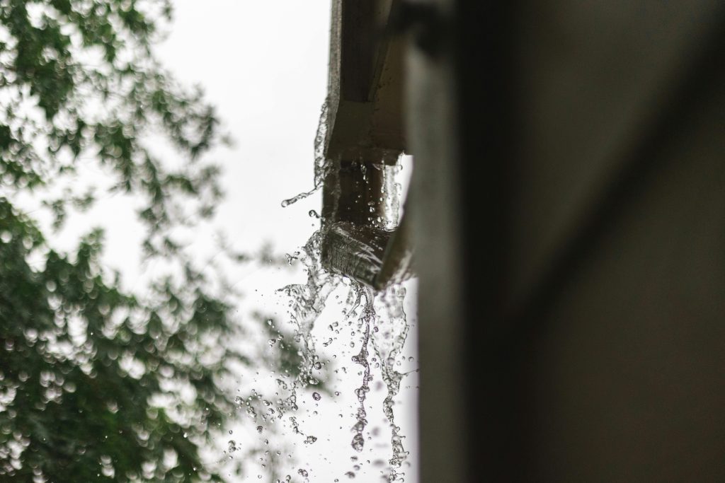 Close-up of rainwater pouring from a gutter, captured during a rainfall in Houston.